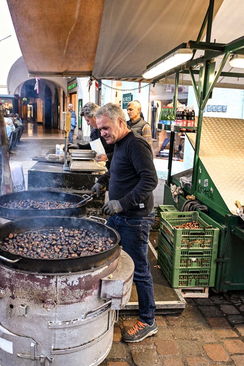 Een man roostert kastanjes in de straten van Bolzano, Italië